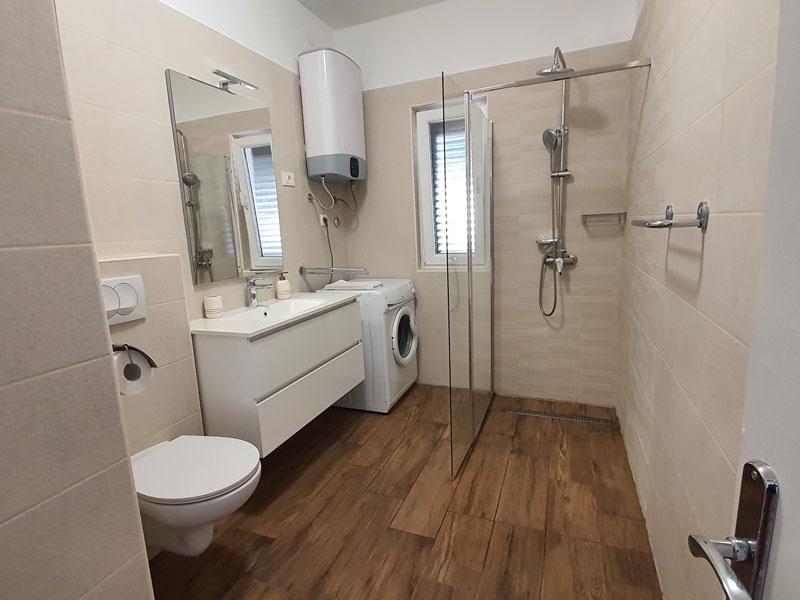 Kopalnica s tušem in pralnim strojem v apartmaju S1-A